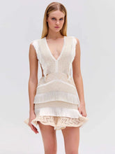 Woman wearing a beige crochet top and shorts on a light gray background